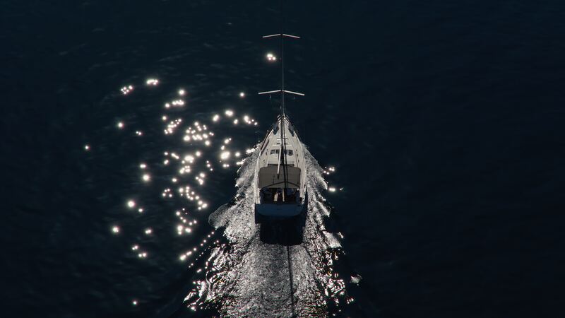 A sailboat seen from above, leaving a white wake through dark water sparkling with sunlight.